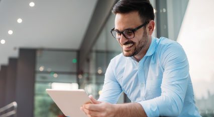 bearded casual corporate man smiling down at a white ipad