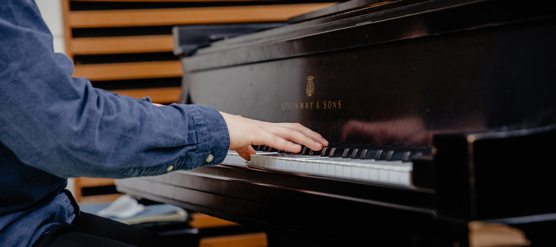 A Normandale music student plays piano in a practice room.