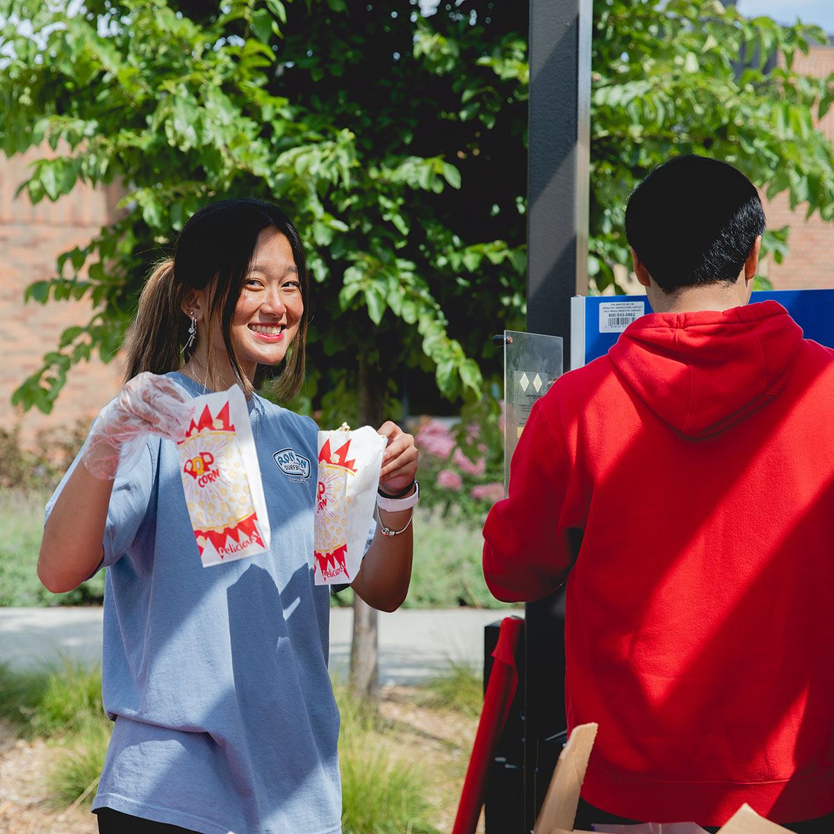 A student serves popcorn at an event.