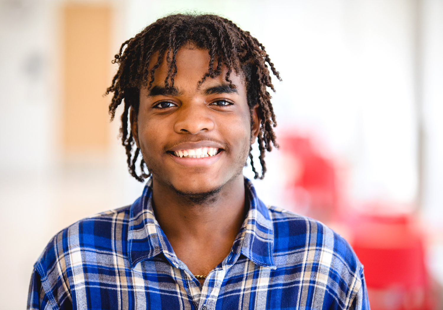 A Normandale student in a blue plaid shirt smiles at the camera.